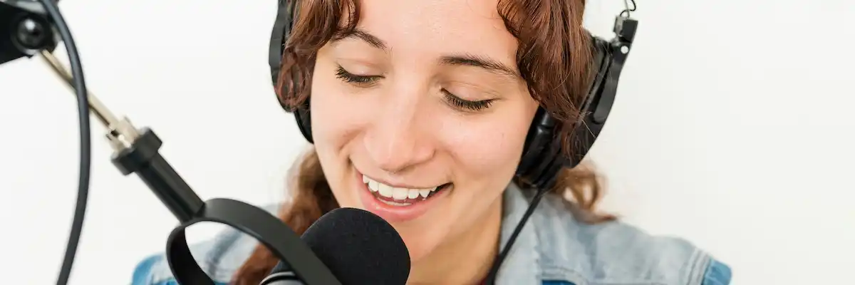 A woman sitting at a microphone, used to illustrate podcast traiing